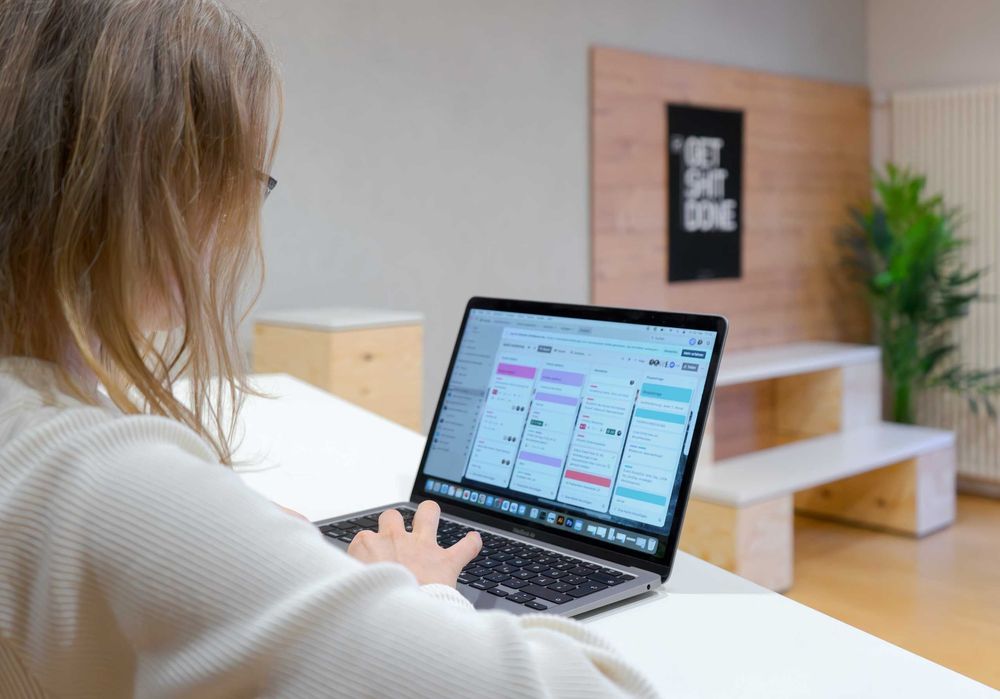 Person arbeitet am Laptop mit digitalem Kanban-Board zur Projektplanung.