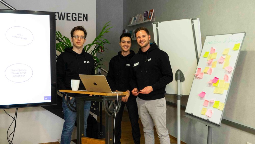 Drei Mitarbeitende Lächeln in die Kamera.