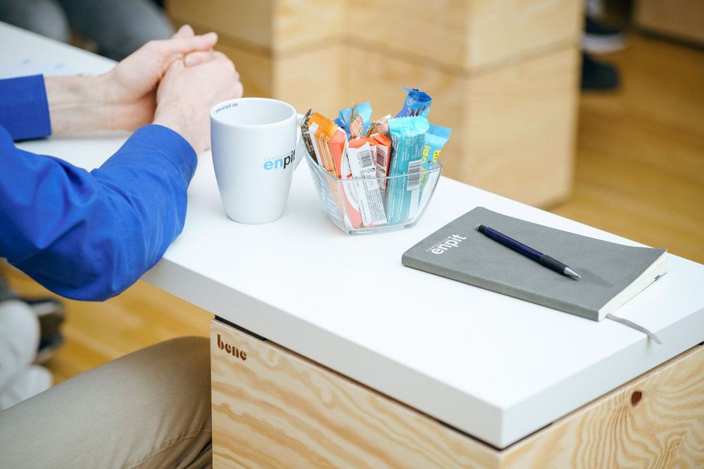 Notizblock und Kaffeetasse auf einem Arbeitsplatz im enpit Büro