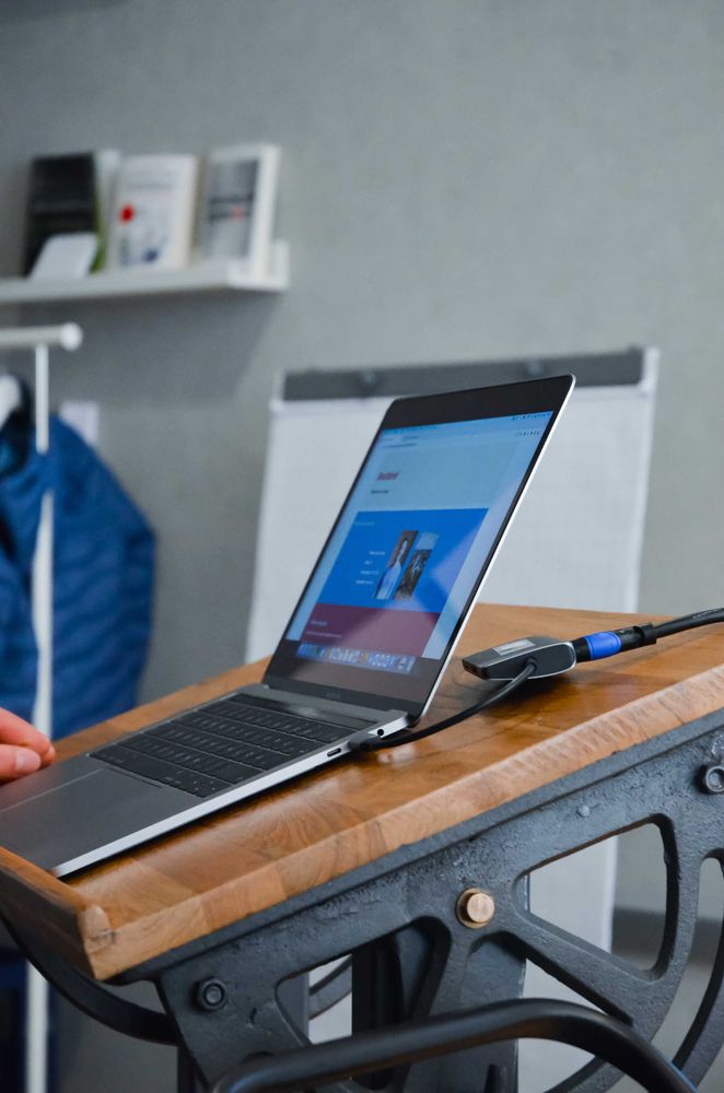 Moderner Arbeitsplatz mit aufgeklapptem Laptop auf einem Holztisch.