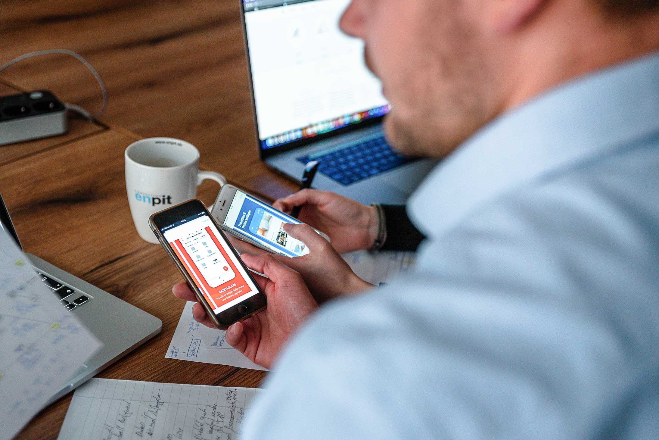 Ein Mann testet eine App auf zwei Smartphones während eines User-Research-Projekts.